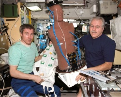 Figure 11.5. ISS astronauts hold the Phantom Torso radiation experiment (Courtesy of NASA).