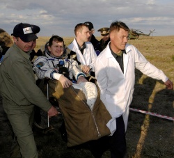 Figure 11.10. An astronaut is carried in a chair from the Soyuz landing site to an inflatable medical tent after an extended mission aboard the ISS (Photo credit NASA/Bill Ingalls).