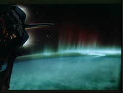 Figure 5.15. Observed from the Space Shuttle are the southern lights (the aurora australis), in a band stretching from East to West, against a background of stars. These are caused by energetic electrons coming down the Earth’s magnetic field lines and hitting atoms and molecules in the upper atmosphere. (Courtesy of NASA)